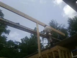 Carpenter setting a ridge beam over a new addition frame — Ice Dam Removal by Roofing Brothers in Gully