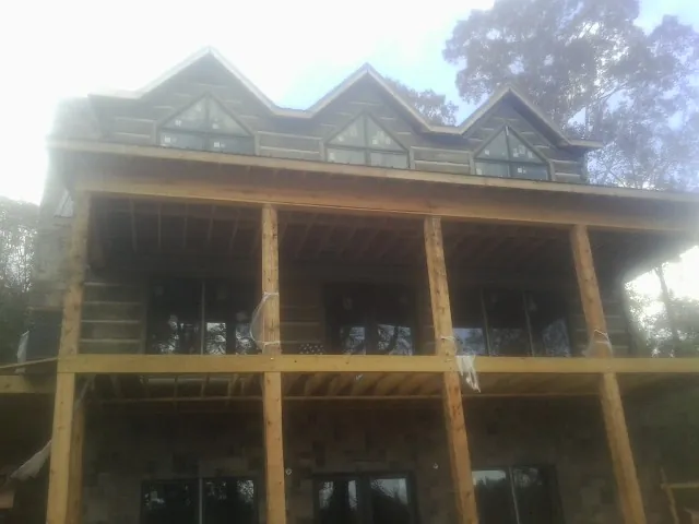 Dormers and porch framing on a large log home under construction — Roof Coating work by our crew in Gully