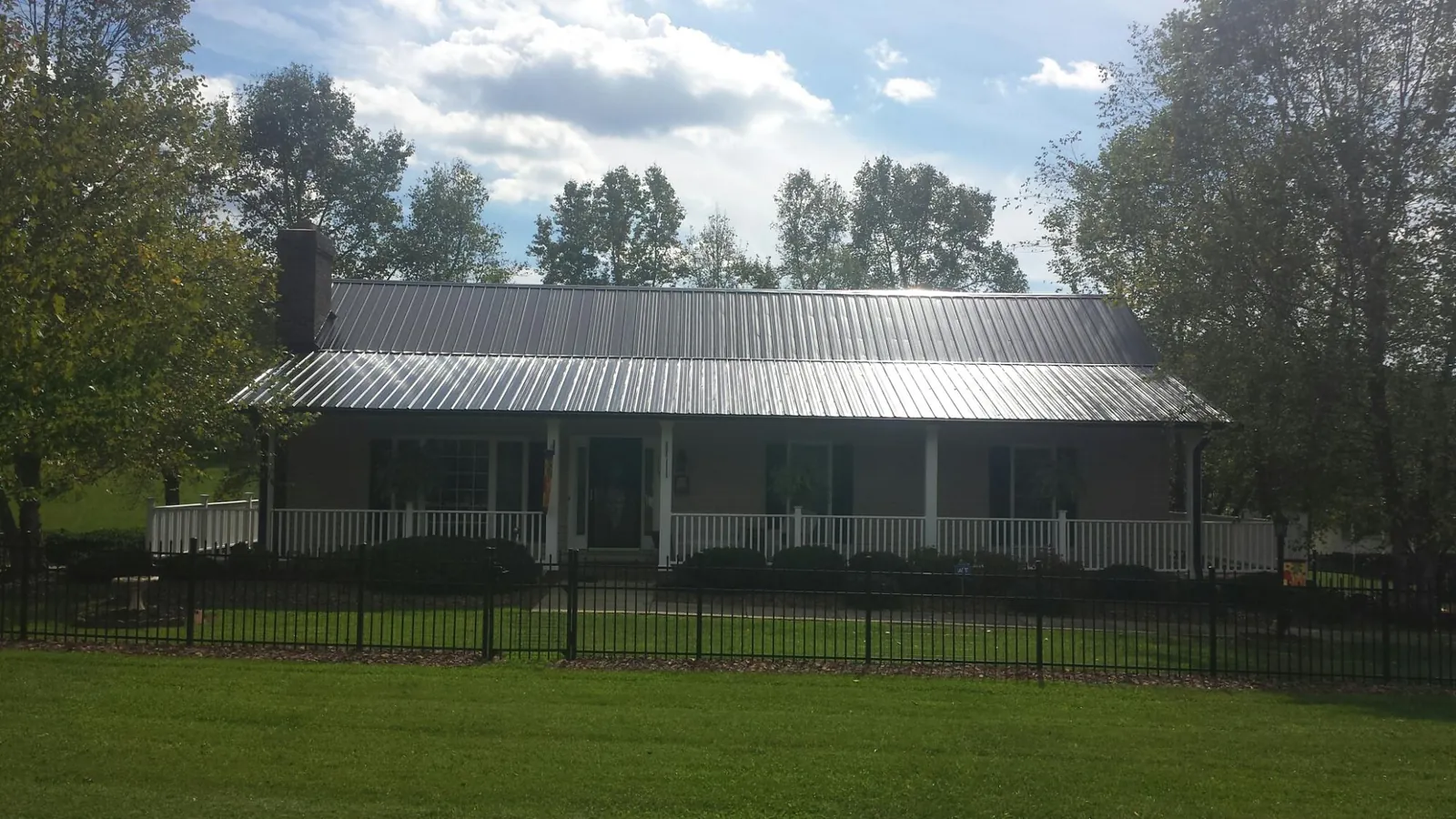 Gray metal roof on a brick ranch with a full width front porch — Gutter Guard Installation work by our crew in Gully